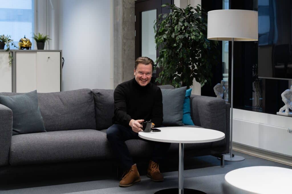 Kuvassa Jääkiekon SM-liiga Oy:n toimitusjohtaja Mikko Pulkkinen istuu sohvalla Fredriksberg A:n toimitilassa