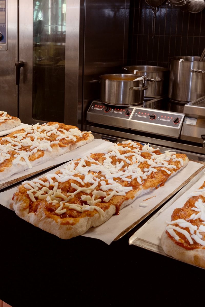 Ravintolan keittiön apupöydällä on kolme raakaa pizzaa odottamassa uuniin menoa.